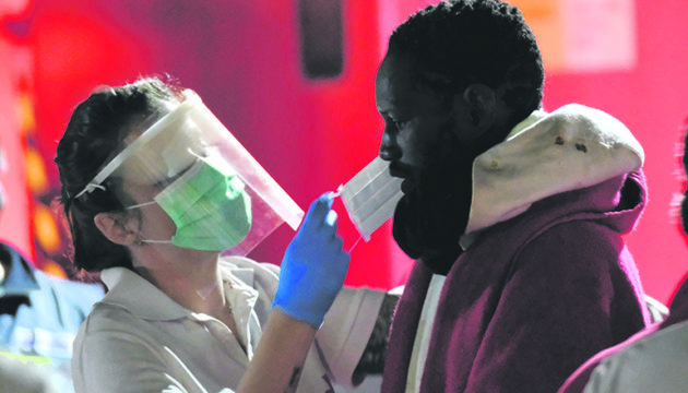 Atemmasken sollen die Helfer und die Mi­granten vor einer möglichen Ansteckung mit dem Coronavirus schützen. Fotos: EFE